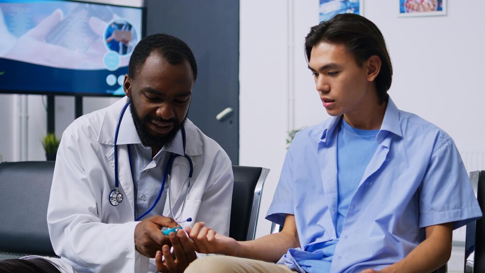 Specialist consulting asian patient with glucometer, measuring insulin and glucose level from blood sample. Doctor and young adult doing diabetic control during checkup visit in hospital reception.