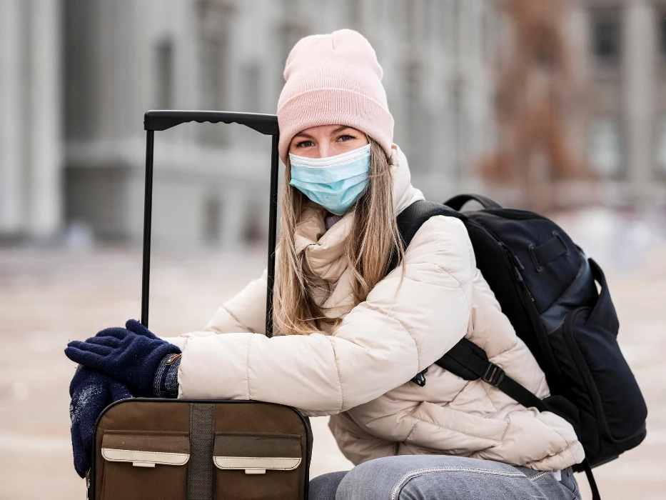 Portrait female student wearing mask and carrying luggage